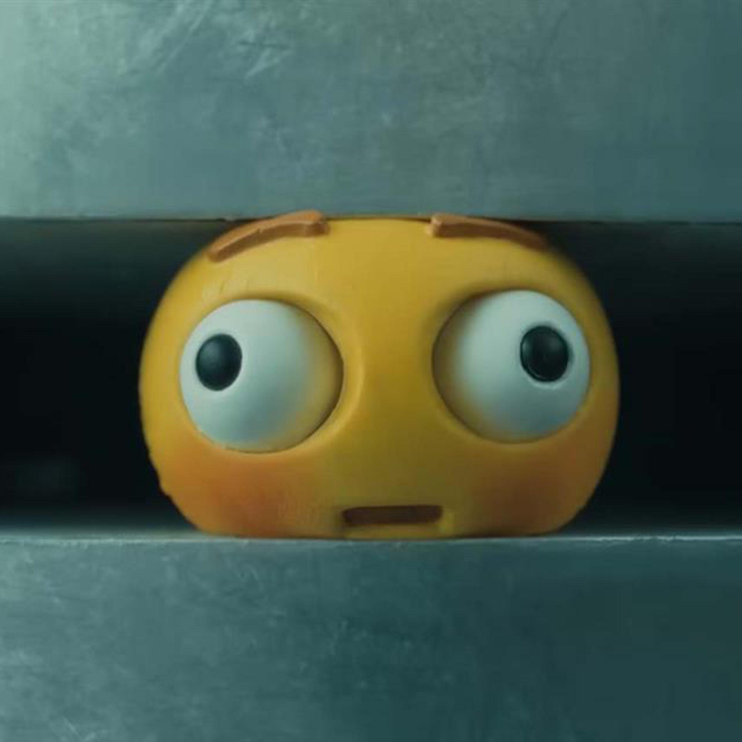 A screenshot of a emoji stress ball being crushed in Apples advert.